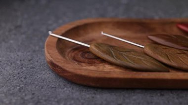 Tahta bir tabağa yerleştirilmiş birkaç tığ işi kancayı gösteren yakın açılı bir çekim. Detaylı dokular sıcak ve yumuşak aydınlatma altında görünür..