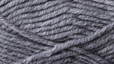 Ilık yumuşak ışık altında ince lifli kalın gri yün bir skein gösteren bir makro kaydırma videosu.