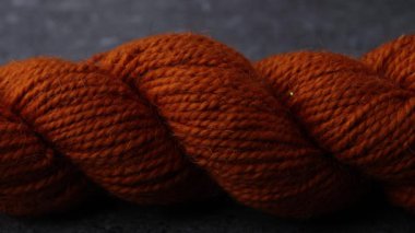 Yumuşak ışık altında yumuşak fiber detay ve sıcak tonlu tıknaz yün iplik skein gösteren bir sürgülü video.