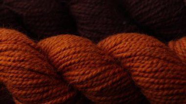 Sıcak tonlar ve yumuşak iplik detaylarıyla birlikte düzenlenmiş birkaç yün yumağını gösteren bir kaydırma videosu.