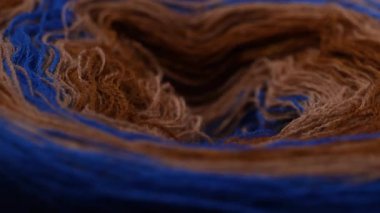Mavi kahverengi bir ipliğin pürüzsüz bir şekilde döndüğü kusursuz bir döngü videosu. Karışık tonlar ve katmanlı iplikler yumuşak desenli kumaş malzemesi oluşturur..
