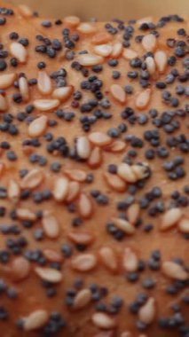 Tohumlu simit biçimli bir çörek makro yakın plan döndürür ve basit bir masa başı ayarında pürüzsüz bir döngü olarak görünür.