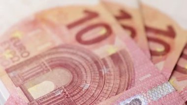 Yazılı dokuları, renk ayrıntılarını ve yüzey şekillerini pürüzsüz bir döngüde gösteren, birlikte düzenlenmiş birkaç on avroluk banknotun dönüşümlü bir makro görüntüsü.