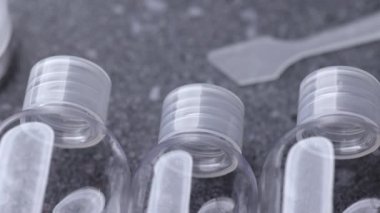 Gri taştan bir yüzeye yerleştirilmiş temiz kozmetik seyahat şişelerinin pürüzsüz bir tablosu, tek tip şekilleri, plastik dokuyu ve temiz kompozisyonu vurguluyor..