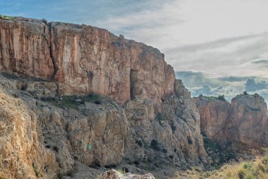 Arbel Dağı 'nın yükselen kaya oluşumu dramatik bulutlu gökyüzünün altındaki mağaralarla birlikte.