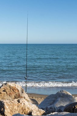 Kumsalda güneşli bir günde kumsalda balık oltası, dinlenme ve rahatlama sunar.