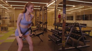 Kablolu TV makinesinde kollarını ve trisepslerini çalıştıran sportif kadın, güç, dayanıklılık ve tonlama, lüks spor salonunda spor, kararlılık, güç, sağlıklı aktif yaşam tarzı konsepti..