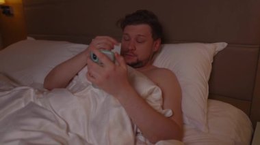 Uykusuzluk sorunu olan gergin genç bir adam geceleri yatakta yatarken endişeyle telefonunu karıştırıyor. Sosyal medyayı kontrol etmekten ya da kötü haber okumaktan, uykusuzlukla boğuşmaktan uyuyamıyor.