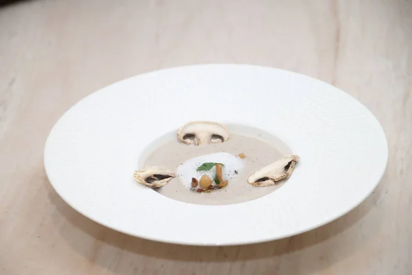 Beyaz köpük, taze soğan ve kuru mantar dilimlerini sunan kremalı gurme mantar çorbası ince yemek kavramları için uygun minimalist beyaz tabakta dizilmiş.