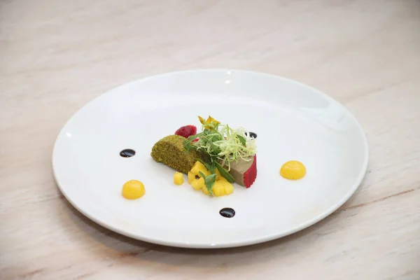 Pate, kırmızı gelee, şam fıstığı parçacıkları, mango küpleri, taze yeşillikler, ahududu unsurları ve balzamik sirke azaltma içeren gurme aperatifleri, sofistike bir mutfak yaratımı sergiliyor