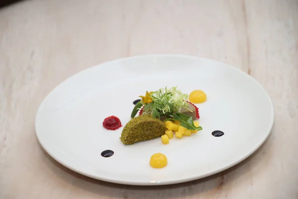 Gurme aperatifi beyaz bir tabakta ince bir renk, doku ve malzeme karışımı sunarak damak tadı için sofistike bir mutfak deneyimini temsil ediyor.