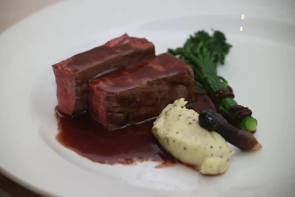 Kırmızı şarap indirgenmiş gurme sığır filetosu, kremalı mantarlı patates püresi ve brokolini beyaz tabakta zarif bir ızgara ana yemek için.