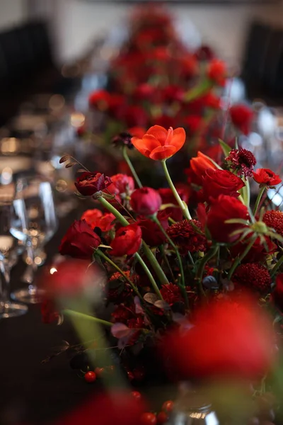 Kırmızı ve turuncu çiçekli süs çiçekleri, yumuşak bokeh 'te güller ve böğürtlenler, düğünler için sıcak, romantik masa gösterileri, yıldönümleri ve samimi akşam yemekleri.