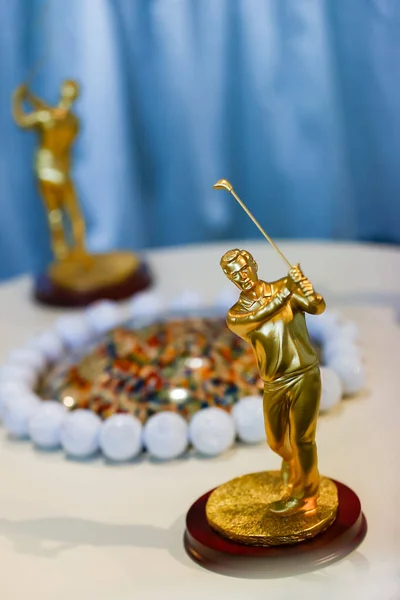 Golfçülerin salıncakta sallandığını gösteren altın golf ödülleri, golf şampiyonlarının kupaları parlak heykelcikler, golf turnuvaları ve şampiyonalarda zafer ve başarıyı simgeleyen, masada sergilenen golf şampiyonu ödülü.