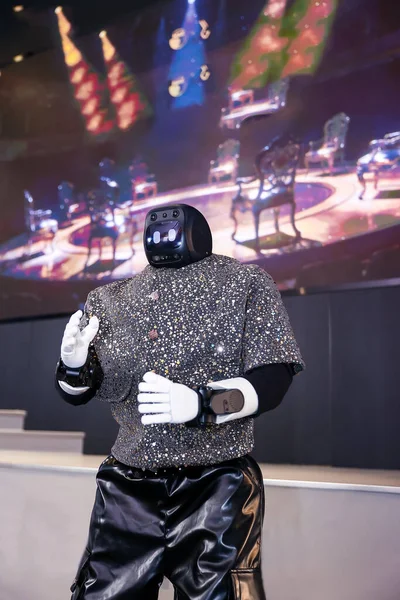 Robot gösterici, bir eğlence etkinliğinde gelişmiş yapay zeka ve gelecek teknolojisini sergiliyor. Parlak bir bluz giyiyor ve seyirciyle etkileşimde.