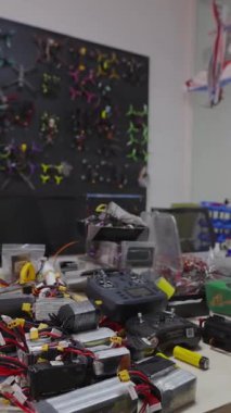 Bir sürü lityum polimer batarya, radyo vericisi, fpv yarış araçlarını monte etmek ve onarmak için yedek parça ve duvarda asılı çerçevelerin koleksiyonu ile dikey atölye çalışması