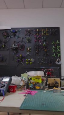 Garaj askeri donanım Fpv drone 'ları inşa etti. İHA' ların yapımı ve onarımı için gerekli malzemeler, arka duvarda sergilenen özel yapım yarış kuadkopterleri ile birlikte.