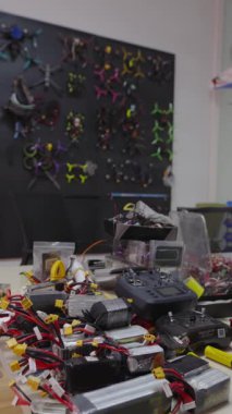 FPV İHA parçaları, bataryalar, kontrolörler, elektronik aletler ile dolu askeri mühendislik atölyesinin dikey çekimi, savaş için yeniden tasarlanmış sivil insansız hava aracı teknolojisi ve modern askeri