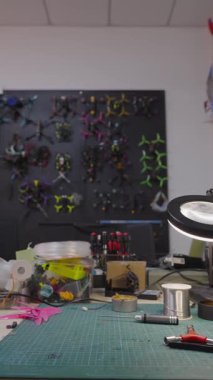 Özel fpv yarış araçları, askeri çatışmalarda kullanılan düşük maliyetli sivil teknolojiler, arka planda duvarda sergilenen fpv kuadkopterlerinin koleksiyonu, inşa için araç ve parçalarla dolu çalışma tezgahı