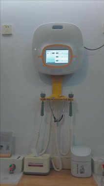 Dijital dokunmatik ekranlı modern tıbbi tanı cihazı ve bir hastane ya da klinikte duvara monte edilmiş çeşitli sensörler, sağlık ve teletıp hizmetlerinin geleceğini temsil ediyor.