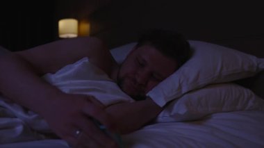 Adam, gece geç saatlerde yatağında uyuyakalmadan önce akıllı telefondan sosyal medyaya mesaj atıyor. İnternetteki iletişimin tadını çıkarıyor. Uykusuzluk çeken telefon bağımlılığından muzdarip.