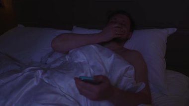 Uykulu adam gece yatağında yatarken telefonunu kullanıyor. İnternette kötü haberleri okuduktan sonra şok oluyor ve üzülüyor. Anksiyete, depresyon, kıyamet kopan bağımlılık.