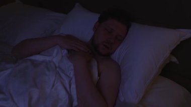 Huzursuz adam nefes almakta zorlanıyor ve uyku apnesi belirtileri gösteriyor. Stresli kabuslar sırasında gece yatağında nefes almak için hareket ediyor ve nefes nefese kalıyor. Bu da ciddi bir sağlık bozukluğunu temsil ediyor.