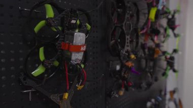 Fpv yarış kuadkopterleri siyah tahta duvarda asılı duruyor, insansız hava araçları ve hava araçlarını uçurmak için hazırlanmış bir koleksiyon.