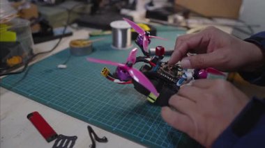 Modern bir insansız hava aracı üretim tesisinde, bir fabrika tezgahına FPV drone parçaları montajı, pervaneler ve elektronik modüller kurulumu