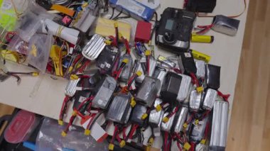 İnsansız hava aracı bataryaları, kablolar, elektronik modüller bir çalışma yüzeyi boyunca yayılmış, insansız hava sistemlerinin taktiksel konuşlanma için hazırlıklarını ve montajını gösteriyor, modern savaş operasyonlarını.