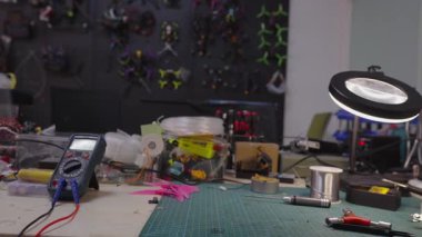 Çeşitli araçları içeren elektronik tezgah, çoklu metre, büyütme lambası, lehimleme malzemeleri ve bileşenleri, montaj, onarım ve mühendislik kavramlarını temsil eden