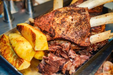 Kavrulmuş sığır kaburgası ve ızgara ananas dilimleriyle metal servis tepsisinde et, açık büfede ya da barbeküde servis edilmeye hazır, lezzetli yemek kavramlarını ön plana çıkarıyor.