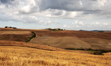 San Quirico d 'Orcia' da - İtalya - Ağustos 2020 - Toskana kırsalında buğday tarlaları ve izole edilmiş bir kırsal ev