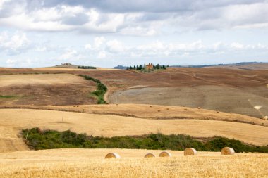 San Quirico d 'Orcia' da - İtalya - Ağustos 2020 - Toskana kırsalında buğday tarlaları ve izole edilmiş bir kırsal ev