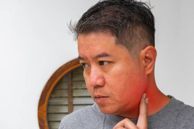 Boynu şişmiş ve bademcik iltihabından kızarmış Asyalı bir adam. Boğaz ağrısı, ENT kliniği veya fotokopi alanı olan iltihap tedavisi reklamları için idealdir..