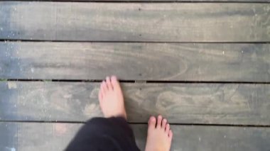 Yıpranmış ahşap kalaslara, doğal dokulara, yalın ayak hareketlere ve yukarıdan dikkatle çekilen yürüyüşlere yavaş çekimde adım atın..