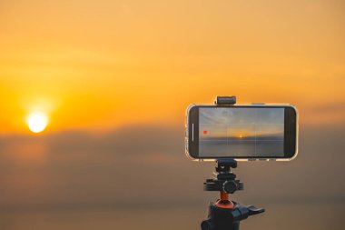 Altın saat yakalama, tripod çerçeveli akıllı telefon sakin suda gün batımı seyahat reklamları, teknoloji meraklısı arka planlar ya da huzurlu tatil ekran koruyucuları için mükemmel..