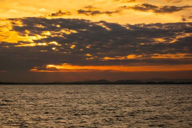 Dramatik bulutlar ve doğa esinlenilmiş duvar kağıdı veya ekran koruyucu için sıcak yansıtıcı ile sakin su üzerinde altın gün batımı.