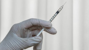 Eldivenli el aşı şırıngasını tutuyor, kesin enjeksiyon için hazır. Modern tıp uygulamalarında bağışıklık, koruma ve profesyonel sağlık hizmetlerinin sembolü.
