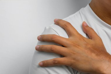 Rahatsızlık içindeki omzu kavramak, kas ağrısını, tıbbi tedaviyi ve daha iyi sağlık ve iyileşme tedavisini sembolize etmek.