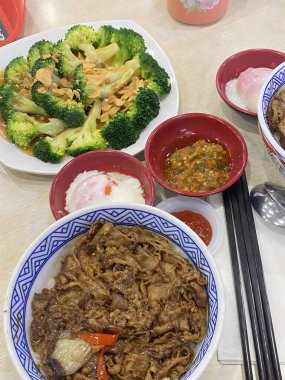 Yakın plan Asya erişte kasesi, yanında da kızartılmış brokoli ve çeşitli soslar.