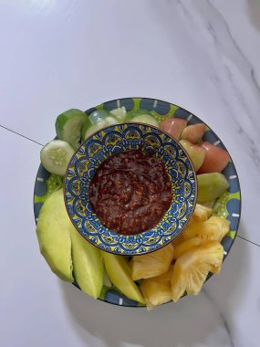 Dilimlenmiş mango, ananas ve çikolata soslu renkli meyve tabağı.