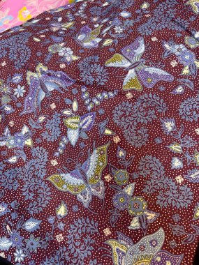 Zengin kırmızı kumaş arka planında karmaşık çiçek ve kelebek tasarımı