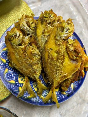 Canlı, mavi ve beyaz desenli bir masa örtüsünde servis edilen kızarmış tavuk.