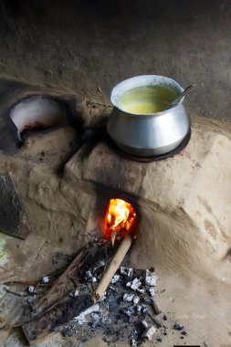 Metal tencereli kil soba ateşte kaynıyor.