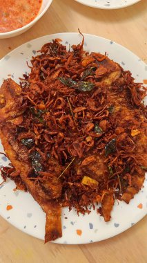 Baharatlı şehriye, sebzeli, beyaz tabakta ve arka planda diğer yemeklerle karıştırılmış..