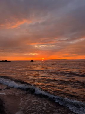 Huzurlu okyanus manzarası alacakaranlıkta canlı turuncu gökyüzü