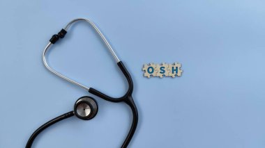 Ahşap bulmacalı, izole edilmiş mavi arka plan steteskop, OSH metni. Mesleki Güvenlik ve Sağlık Konsepti
