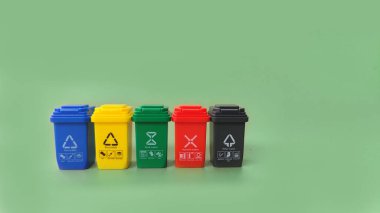 Yeşil arka planda izole edilmiş ayrı plastik, kağıt, metal ve organik çöp kutusu koleksiyonu için mavi, sarı, yeşil, kırmızı ve siyah kaplar. Geri dönüşüm kavramı