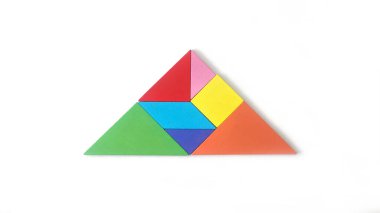 Ayrı bir el, beyaz arka planda ok şeklinde renkli tangram yapbozu tutuyor. Bulmaca konsepti. İlerleme, sonraki adım, büyüme kavramı